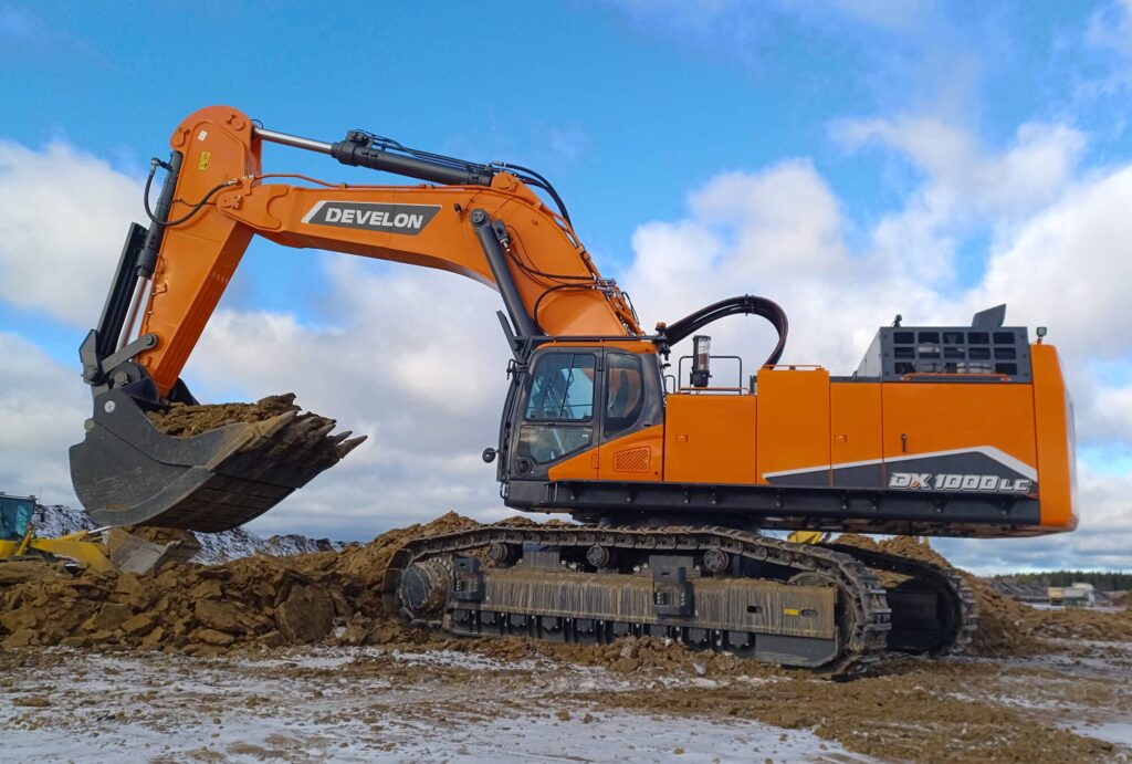 DISA construction equipment excavator lifting soil at a construction site under a cloudy sky.